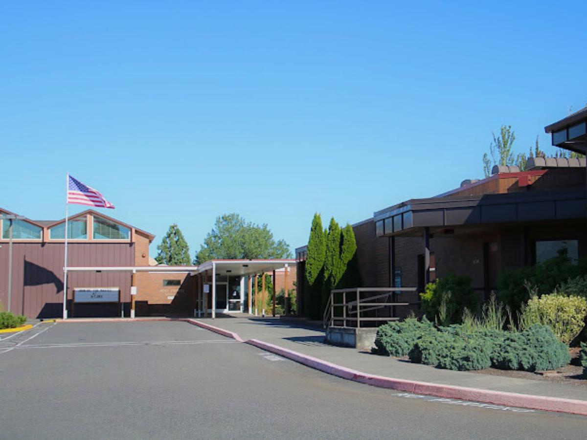 Outside of school showing drive up to school and flag in front of school for article Holy Trinity Catholic School for newcomers moving to Portland.
