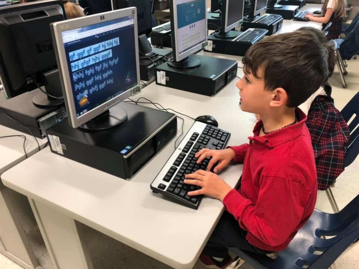 Boy sitting at a computer learning for article St Joseph Catholic School for newcomers to Portland Area.