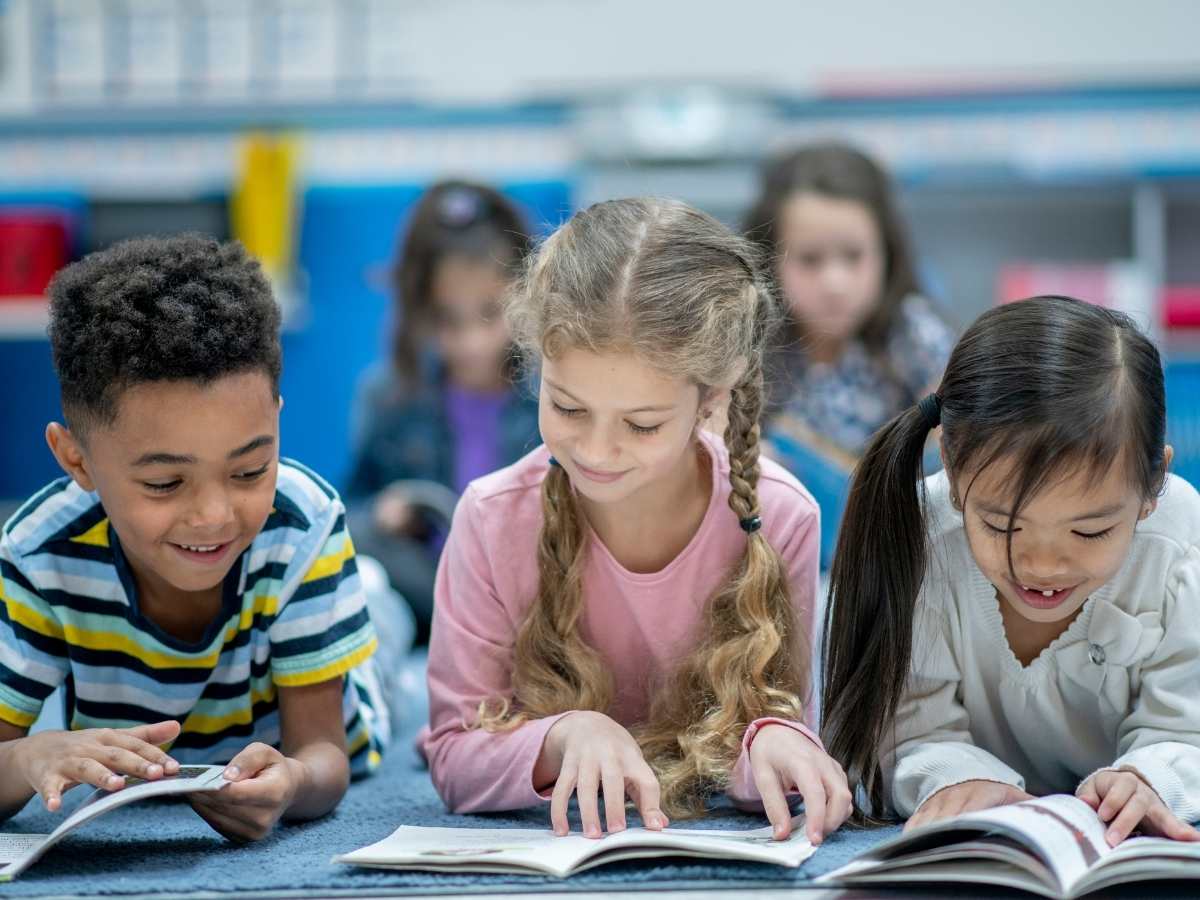 Elementary kids sitting on the floor reading for article Ridgefield School District for newcomers moving to Portland.