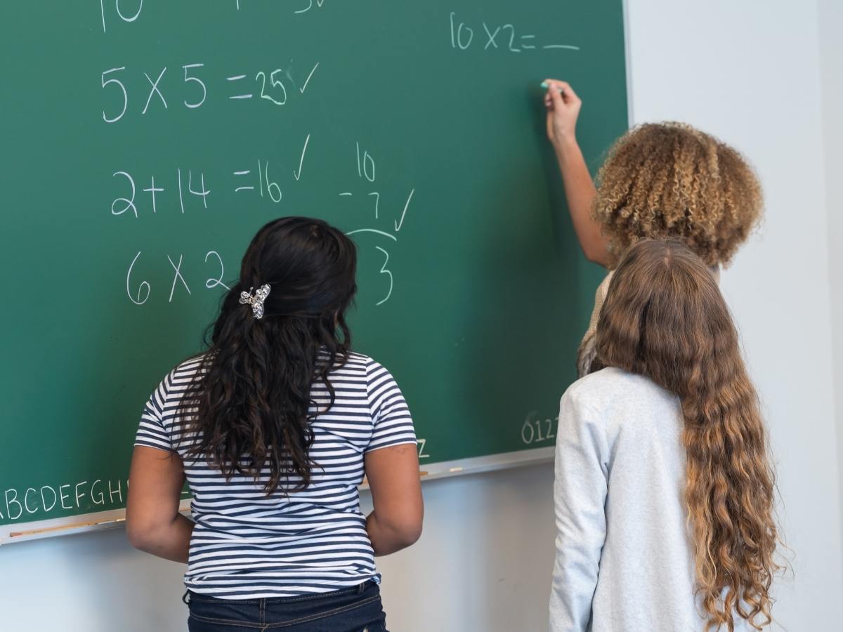 3 students working on math problems on the chalkboard for article David Douglas School District for newcomers moving to Portland area.