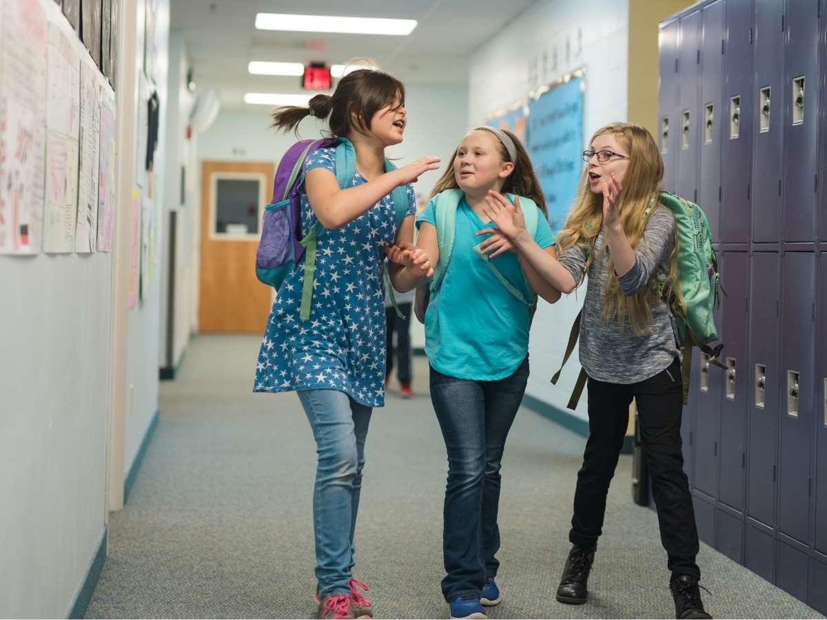 3 girls talking and walking down school hallway for article Beaverton School District for newcomers moving to Portland area.