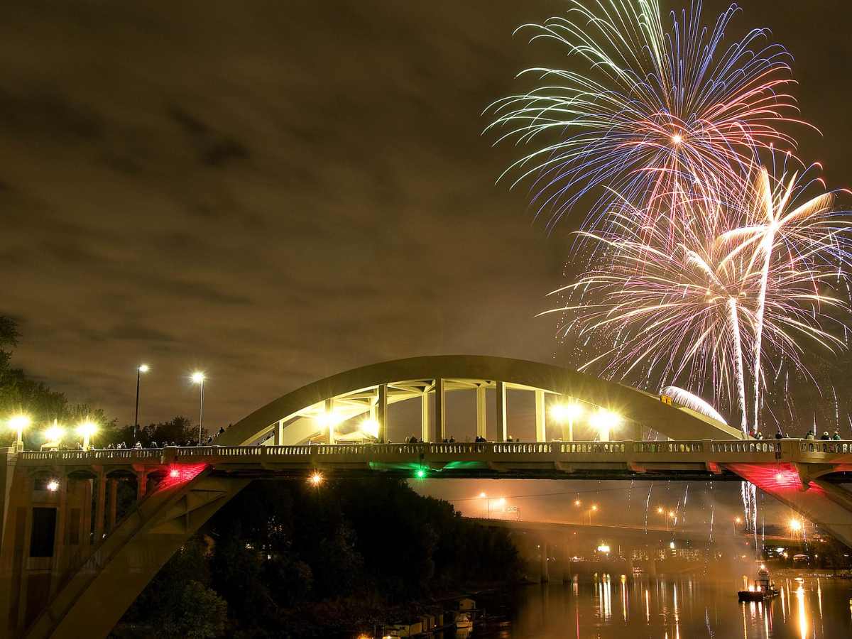 4th of July fireworks over the river with the arched bridge in the foreground for article Oregon City, Oregon for newcomers moving to Portland.