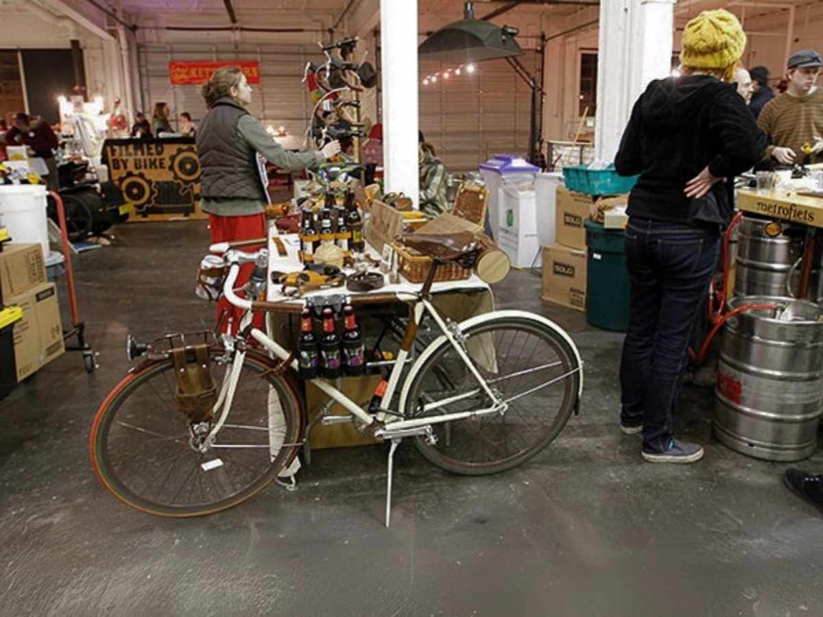 Image of people shopping in a brewery with a bike front and center being used as part of display for beer bottles for article Portland Loves Credit Unions for newcomers moving to Portland.