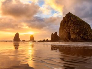 Cannon Beach showing the beach at sunset with the haystack rock formation in the water in the distance for article Discover Cannon Beach: 2025’s Top Coastal Escape for newcomers moving to Portland.