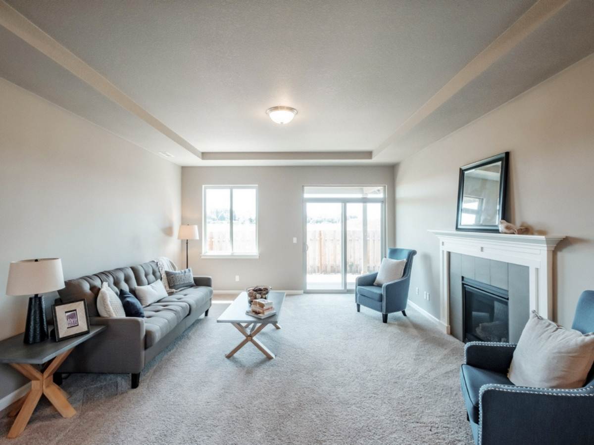 Living room in Stafford Home showing couch on one wall, fireplace on other with chairs flanking in and glass window and door at far end for article Stafford Homes and Land for newcomers moving to Portland.