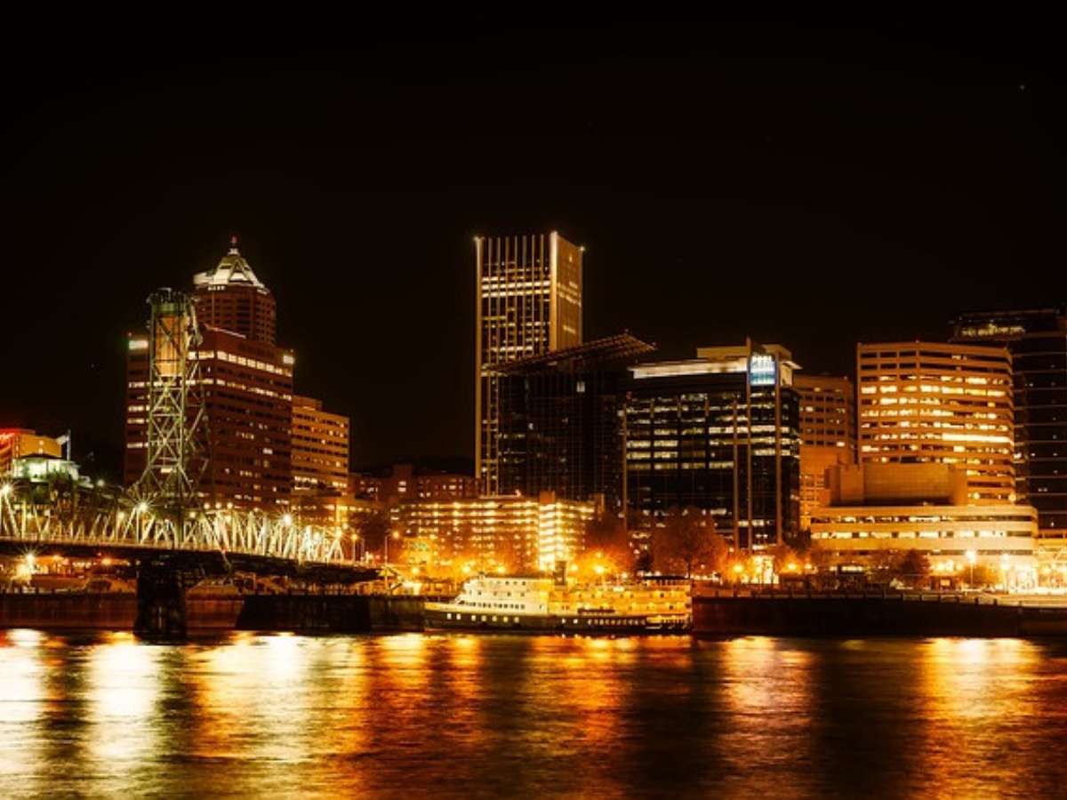 Part of Portland city on the water all lit up at night with a warm yellow glow and black sky for article Portland ranks #9 for best places to live in 2021 for newcomers moving to Portland.