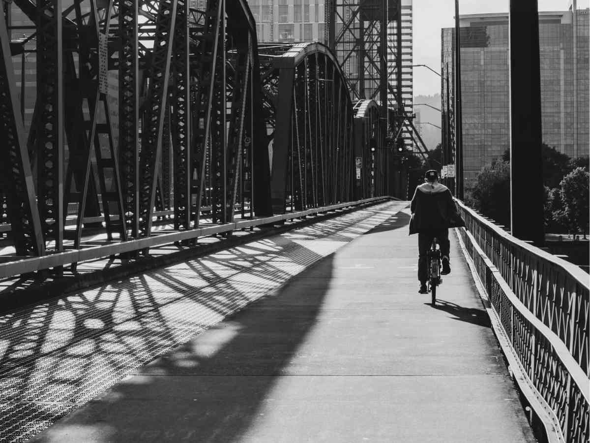 Black and White photo of person riding bike across Portland Bridge for article Information for Newcomers to Portland for newcomers moving to Portland.