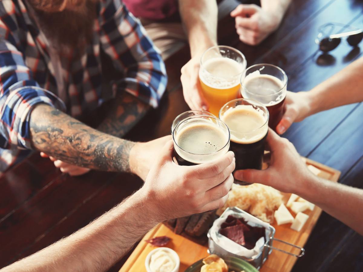 Hands holding beer pints doing cheers for article Tap into Portland's Beer Scene for newcomers moving to Portland.
