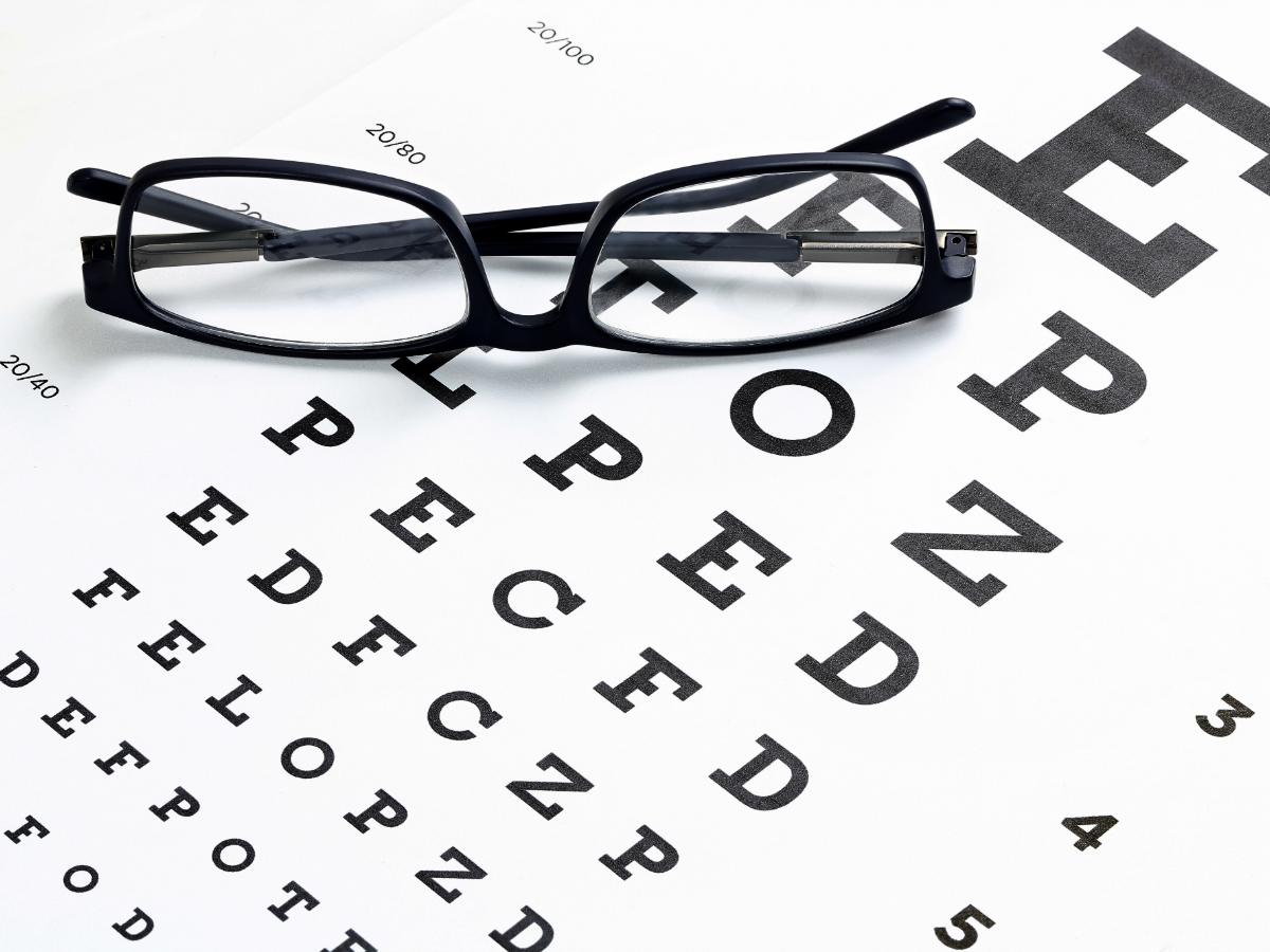 Eye chart with glasses sitting on top of it for article hearing and vision care for seniors in Portland for newcomers retiring in Portland.