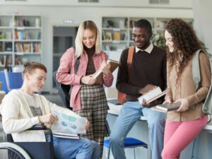 1 student in a wheelchair, 3 standing around him all looking at a study guide. article - 10 Best College Prep High Schools in Portland for newcomers moving to Portland.