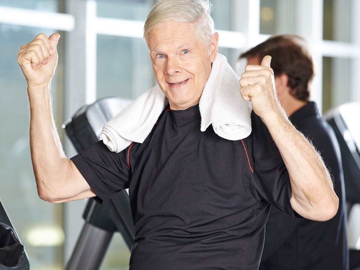 Senior man in fitness center with towel around neck and giving thumbs up for article Top 5 Senior Wellness Programs in Portland for retirees moving to Portland.