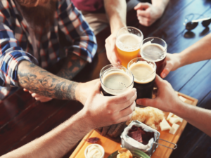 Hands holding beer pints doing cheers.