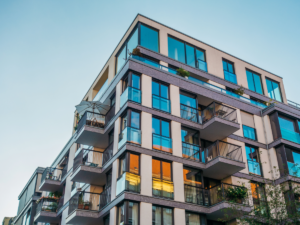 Looking up at corner of modern apartment building with balconies.