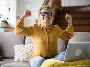 Person celebrating in front of computer after finding contract work online.