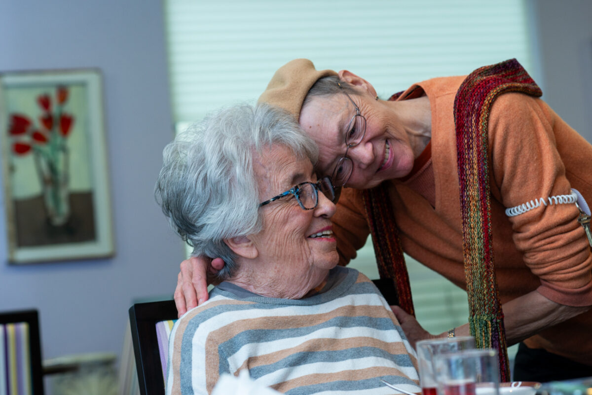 One resident leaning down to hug another.