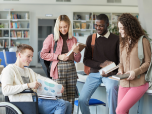 1 student in a wheelchair, 3 standing around him all looking at a study guide. article - 10 Best College Prep High Schools in