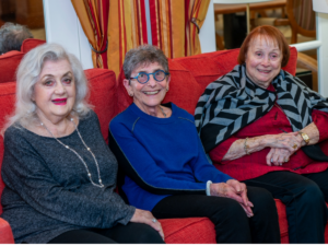 3 women sitting together on a couch at Cedar Sinai Park assisted living community.