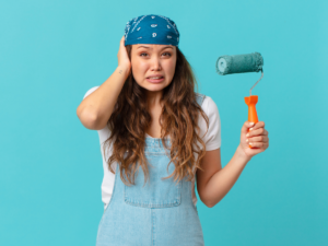 Girl holding paint roller with a whoops look on her face for article 7 Costly Painting Mistakes to Avoid for newcomers moving to Portland.